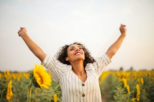 女人站在向日葵田的照片 · 免费素材图片