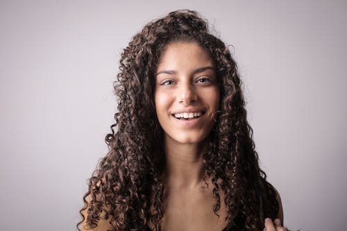 棕色卷发的微笑妇女的肖像照片 · 免费素材图片