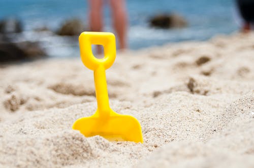 黄铲半埋在海边的沙滩上 · 免费素材图片