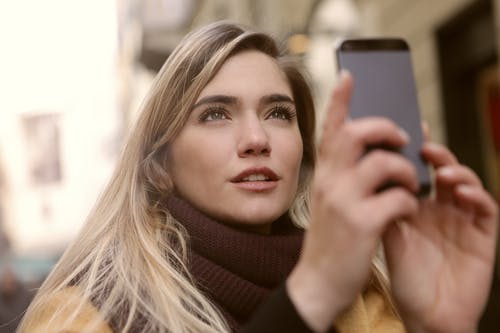 女人拿着智能手机的选择性焦点照片 · 免费素材图片