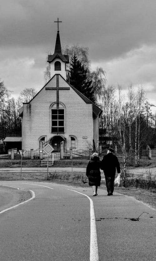 在教堂附近的人行道上行走的人的灰度照片 · 免费素材图片