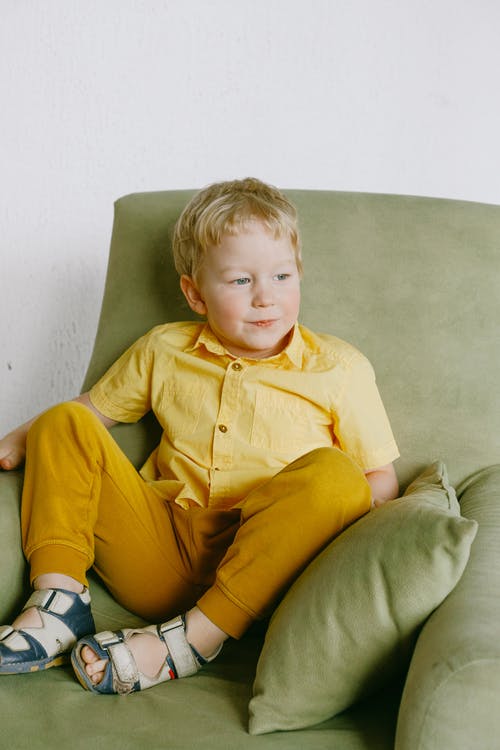 黄色按钮的衬衣的男孩坐在灰色沙发椅子 · 免费素材图片