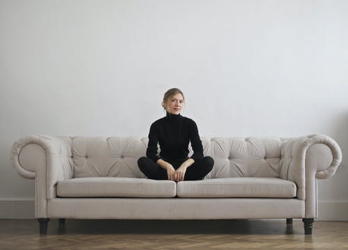 黑色长袖高领毛衣，坐在灰色的墙前的灰色沙发上的女人的照片 · 免费素材图片