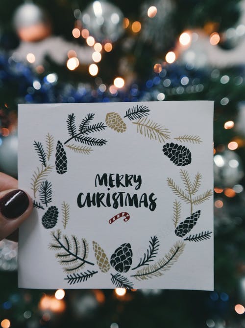 持米色和黑色花卉快乐圣诞贺卡的人 · 免费素材图片