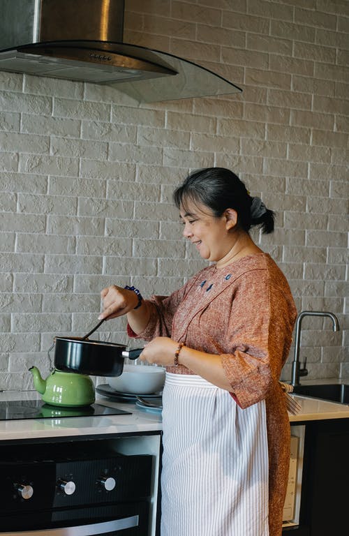 性格开朗的高级亚裔女子搅拌酱在厨房里 · 免费素材图片