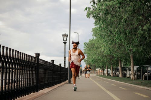 白色背心和红色短裤在路上跑的人 · 免费素材图片