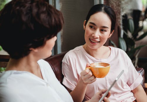 积极亚洲女性坐着咖啡，看着朋友 · 免费素材图片