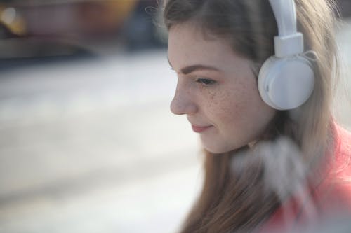 女人听音乐使用白色耳机 · 免费素材图片