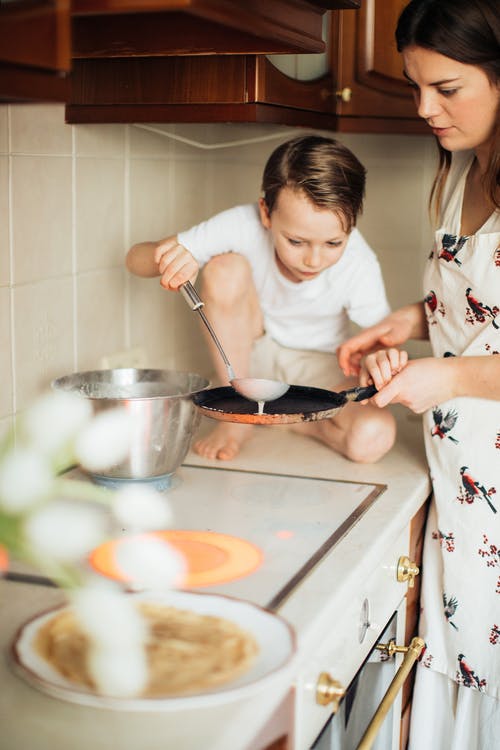 女人教她的孩子如何做饭的照片 · 免费素材图片