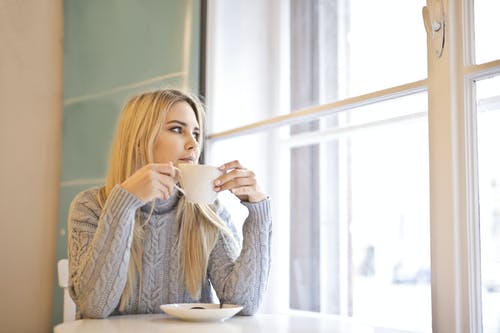 拿着白色陶瓷杯的白色针织毛衣的女人 · 免费素材图片