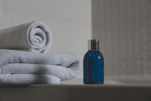 白毛巾旁边的蓝色玻璃瓶 · 免费素材图片