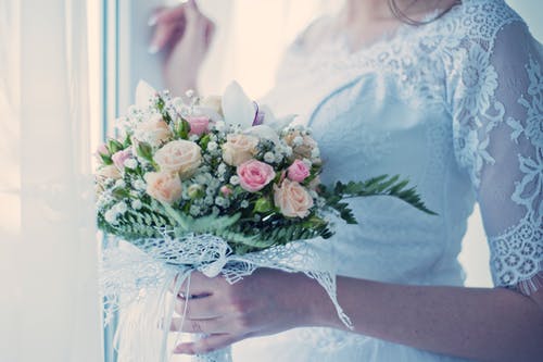 女人抱着白色和粉红色的插花 · 免费素材图片