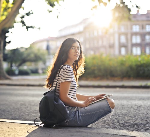 黑色和白色条纹的衬衫和蓝色牛仔牛仔裤，坐在人行道上的女人 · 免费素材图片