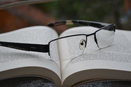 透明眼镜与黑框上已打开的书 · 免费素材图片