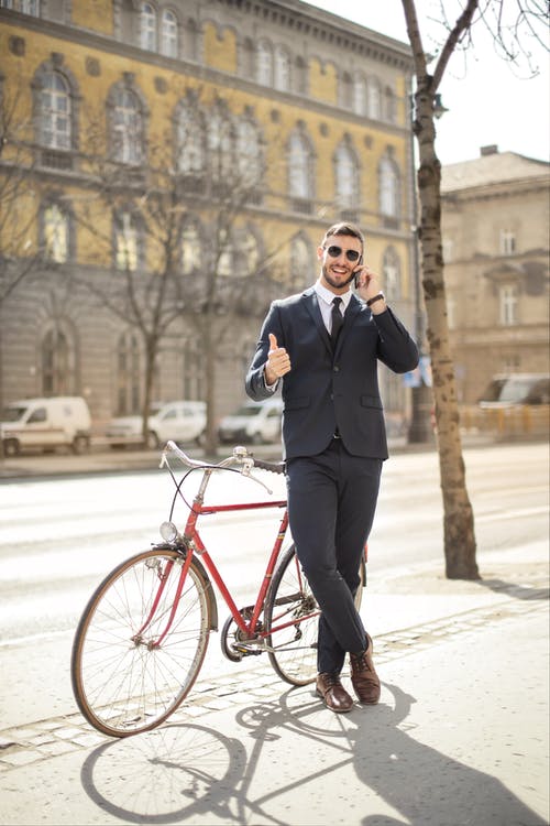 站在红色自行车旁边的黑色西装的男人 · 免费素材图片