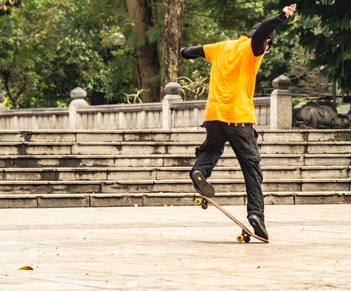 黄色的t恤和黑色的裤子，玩滑板的人 · 免费素材图片