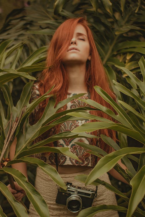 女人站在绿色的植物附近 · 免费素材图片