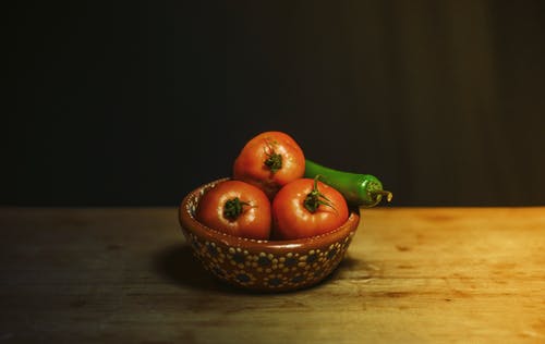 红番茄和绿色辣椒棕色和棕色木制的桌子上的白色花卉陶瓷碗 · 免费素材图片