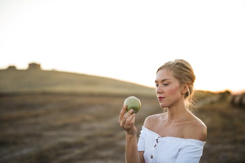 女人的选择聚焦照片在白色的肩膀上持有青苹果的白 · 免费素材图片