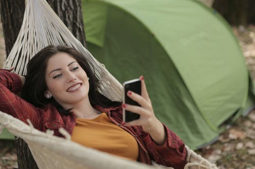 使用手机时躺在吊床上的女人的照片 · 免费素材图片