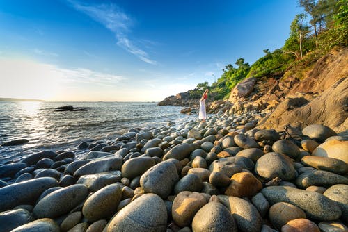 站在多岩石的海岸上的人的照片 · 免费素材图片