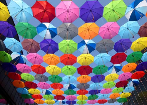 黄色蓝色红色粉红色紫色绿色多彩多姿的开放伞挂在蓝蓝的天空下的字符串 · 免费素材图片