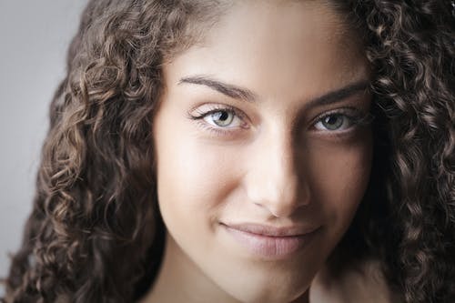 棕色卷发的微笑女人的特写肖像照片 · 免费素材图片
