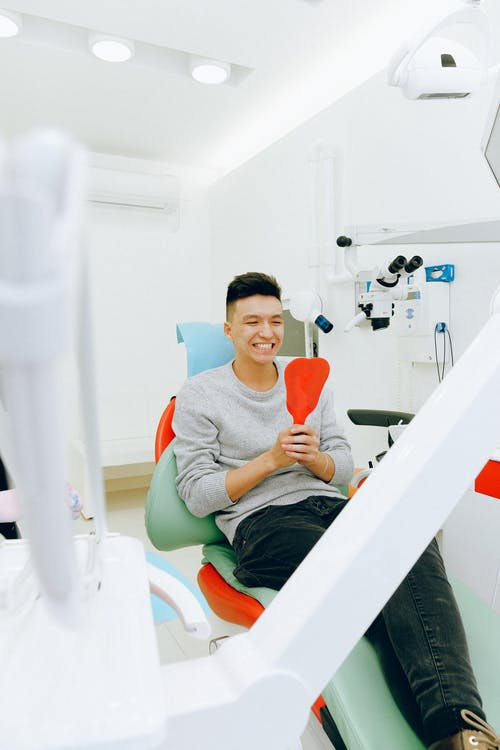 男子坐在牙科椅上 · 免费素材图片