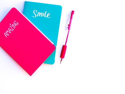 红色点击笔旁边的粉色和蓝色笔记本 · 免费素材图片