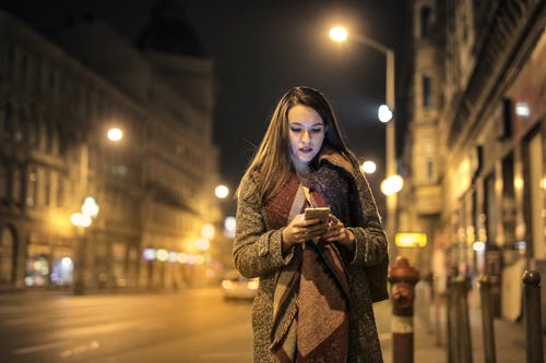 在人行道上拿着智能手机行走的女人 · 免费素材图片