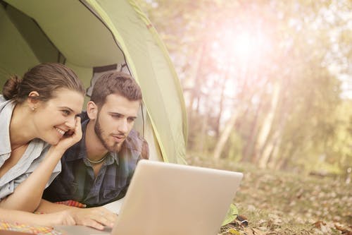 夫妇躺在帐篷里，用电脑笔记本 · 免费素材图片