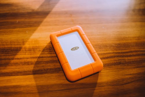在木质表面上的橙色手机壳 · 免费素材图片