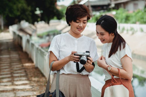 亚洲女人与开朗的最好的朋友分享相机拍照 · 免费素材图片