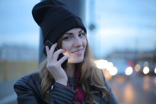 黑色针织帽和黑色皮夹克的女人微笑着 · 免费素材图片