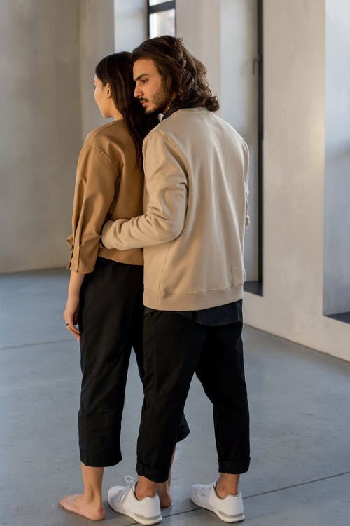 女人和男人在米色的长袖衬衫和黑色的裤子，站在灰色的地板上 · 免费素材图片