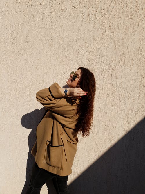 棕色外套混凝土墙附近的女人 · 免费素材图片