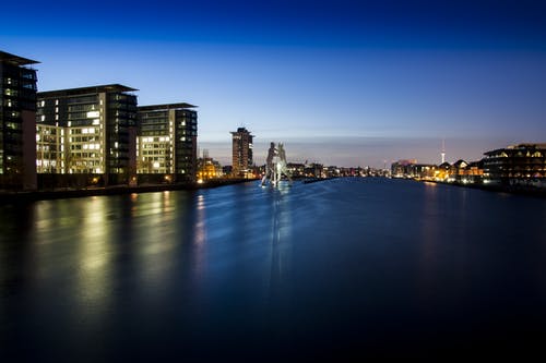 夜间在水体附近的高层闪电建筑物的风景照片 · 免费素材图片