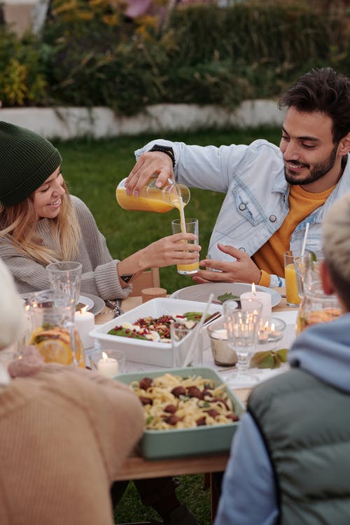 幸福的夫妇和其他人在花园里享用晚餐和饮料 · 免费素材图片