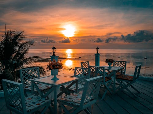 白色的木桌和椅子在日落时分在海边 · 免费素材图片