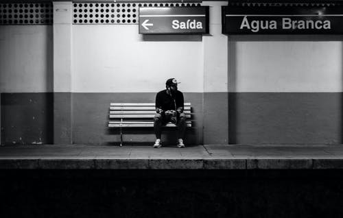 男子坐在火车站的长椅上 · 免费素材图片