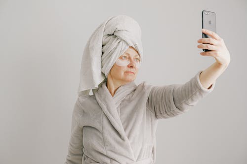 拿着黑色智能手机的灰色浴袍的女人 · 免费素材图片