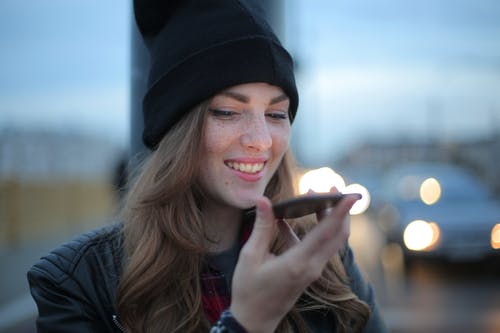 拿着智能手机的黑色针织帽的女人 · 免费素材图片