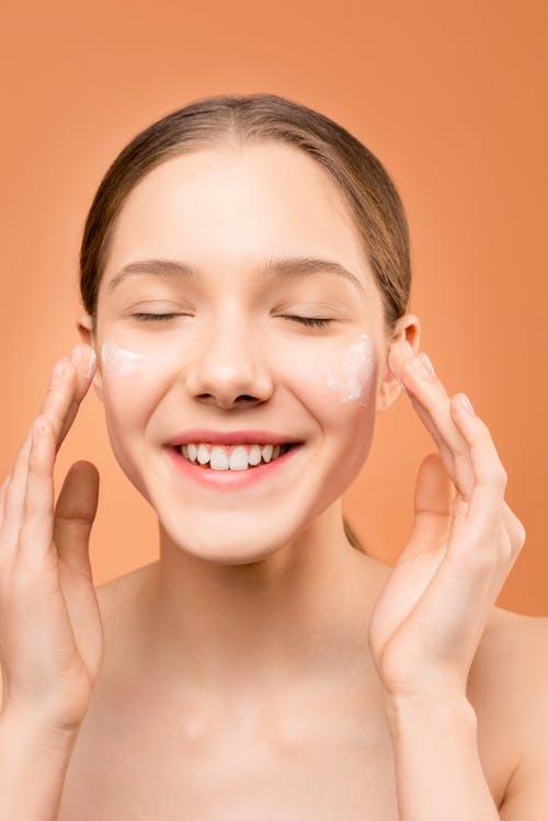 女人在她的脸上应用保湿剂 · 免费素材图片