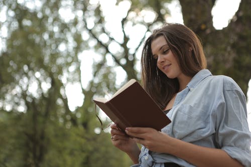 女人抱着和读棕色的书 · 免费素材图片