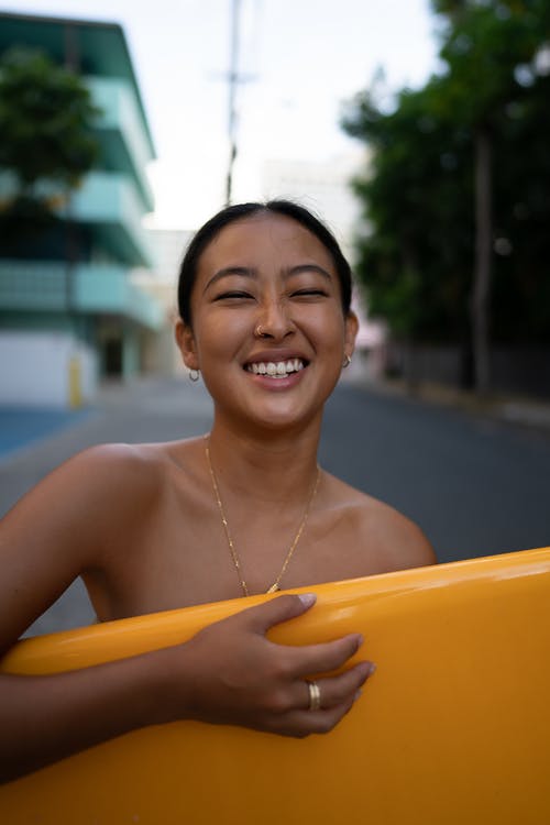 拿着黄色塑料盘子的银色项链的微笑的妇女 · 免费素材图片