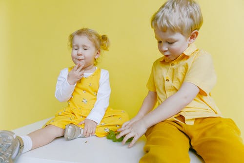 小孩坐在白色的桌子上，一边吃绿葡萄 · 免费素材图片