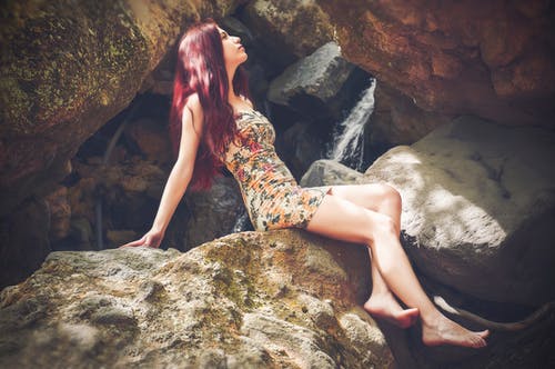Bodycon迷你连衣裙坐在巨石上的女人 · 免费素材图片