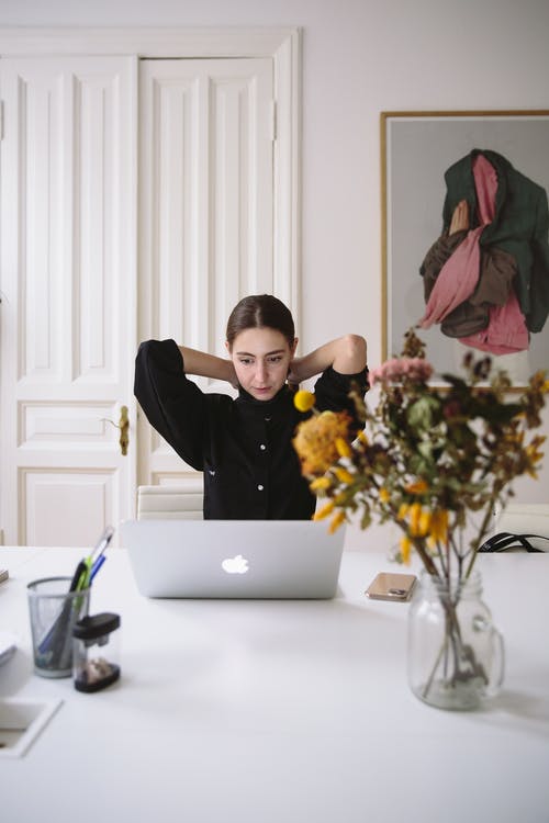 坐在银色笔记本电脑前的黑色上衣的女人 · 免费素材图片