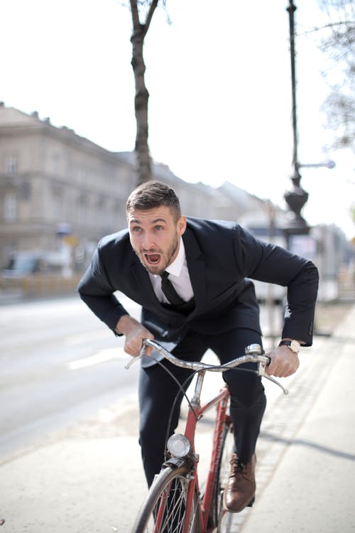 黑色西装外套骑红色自行车的人 · 免费素材图片