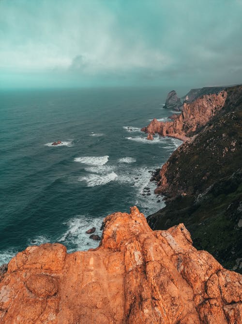 水体旁的棕色岩石地层 · 免费素材图片